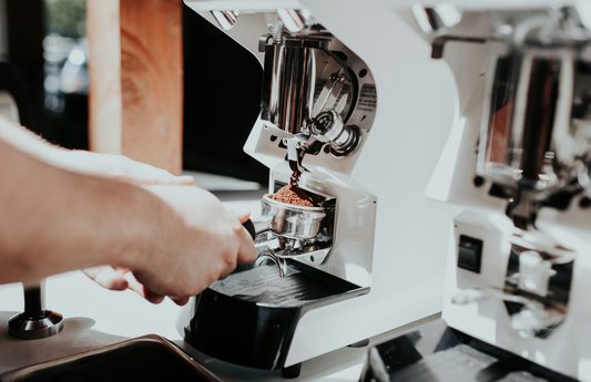 Eine Hand stellt den Mahlgrad an einer Espressomaschine ein, um den perfekten Mahlgrad Kaffee zu erzielen.