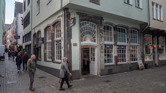 Außenansicht des True Beans Flagship Stores in einer belebten Altstadtstraße mit historischen Gebäuden und Kopfsteinpflaster.