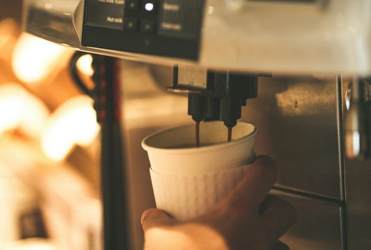 Nahaufnahme eines Kaffeevollautomaten, der frisch gebrühten Kaffee in einen Becher gießt. Der Vollautomat sorgt für eine bequeme und schnelle Zubereitung von Kaffee auf Knopfdruck