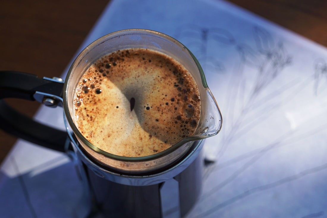 Nahaufnahme einer frisch gebrühten French Press mit goldbrauner Crema