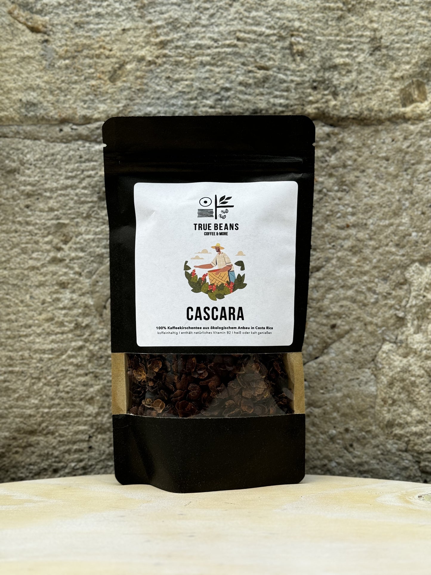 Produktbild von True Beans Cascara Kaffeekirschentee, 100% aus ökologischem Anbau in Costa Rica, verpackt in einer schwarzen Tüte mit einem klaren Sichtfenster und einem weißen Etikett.