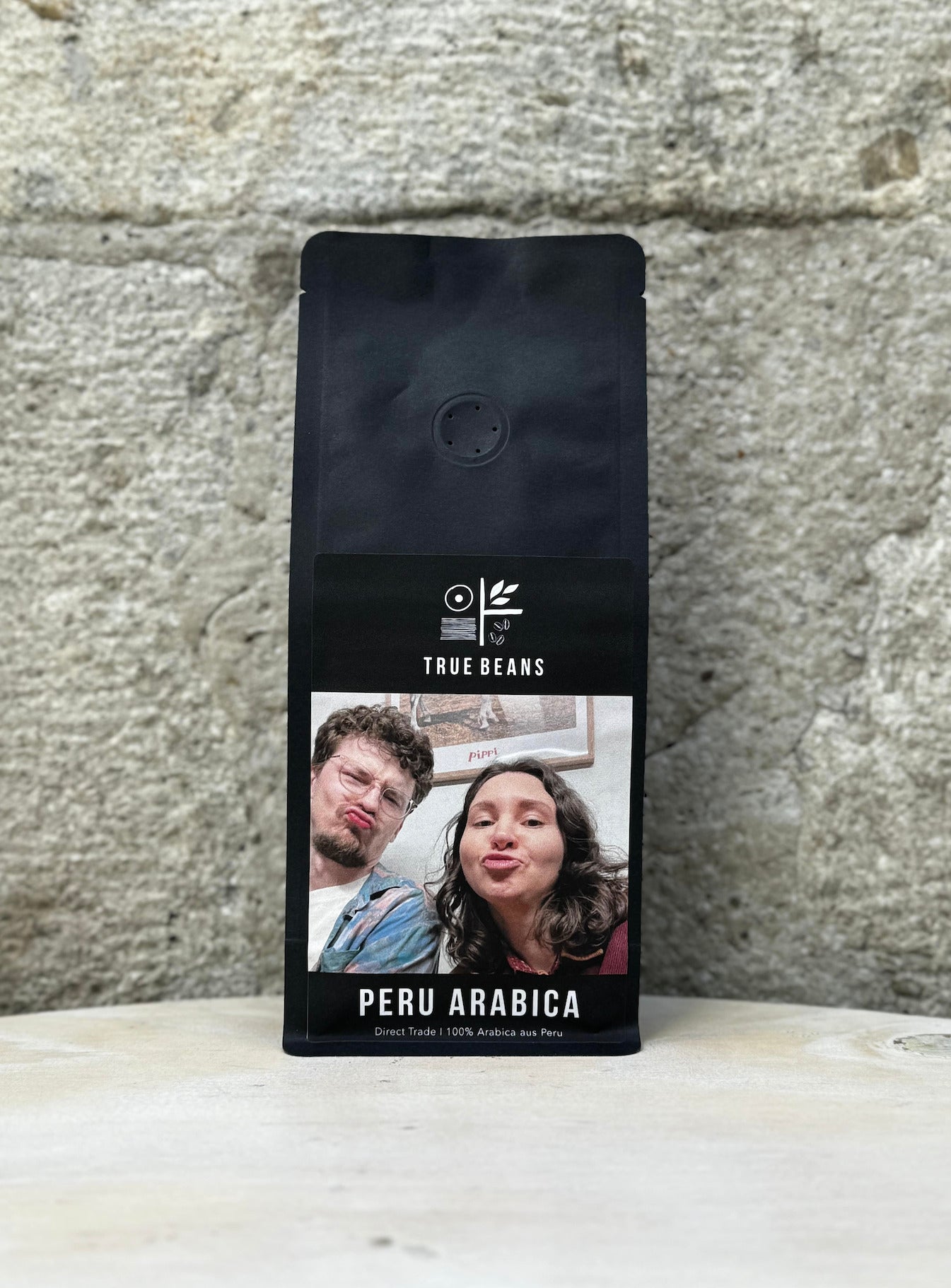 Verpackung von True Beans Peru Arabica Kaffee mit einem individuellen Etikett, das ein Bild von zwei Personen zeigt.