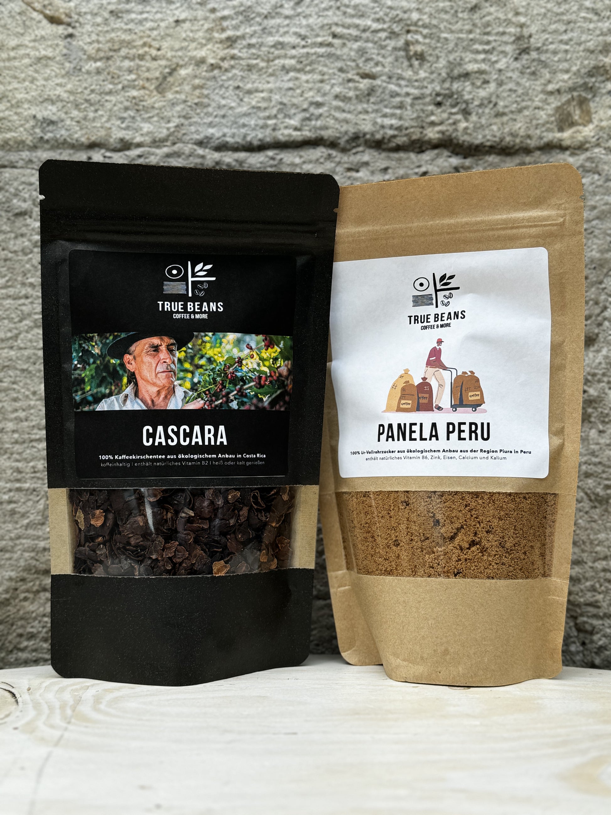 Zwei nachhaltige Produkte von True Beans: "Cascara" links und "Panela Peru" rechts, vor einem hellen Hintergrund auf einem Holztisch.